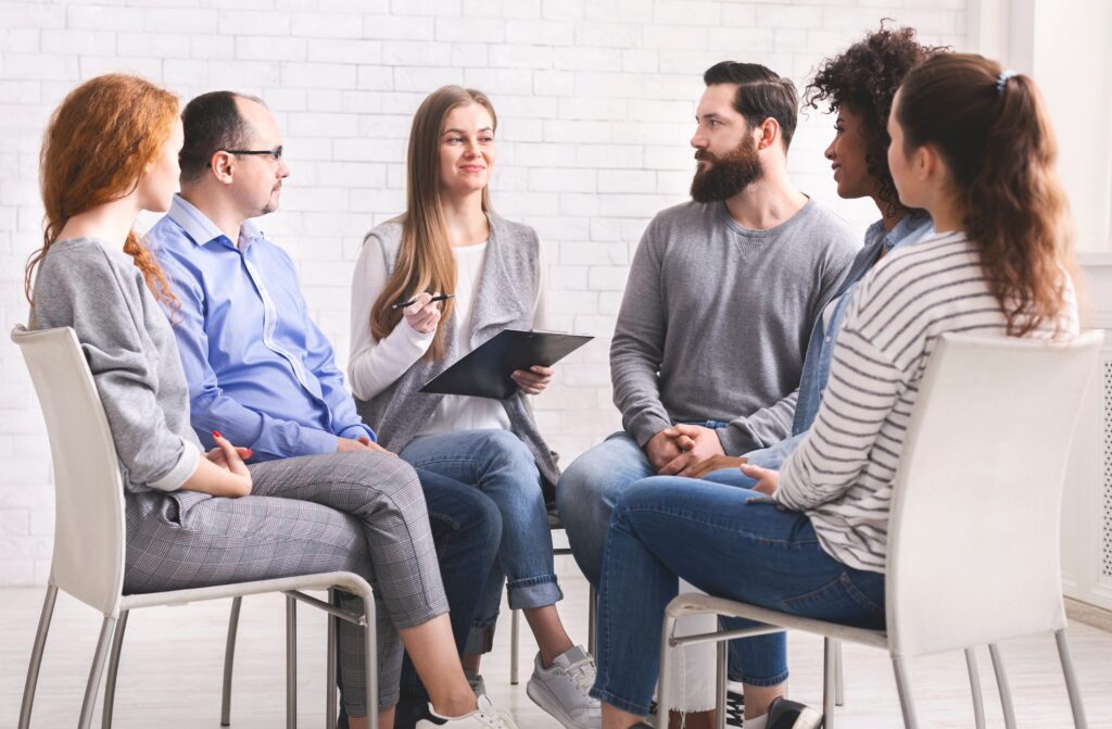 People of different ethnic backgrounds sitting together in a group therapy session, reflecting inpatient healing and community support.